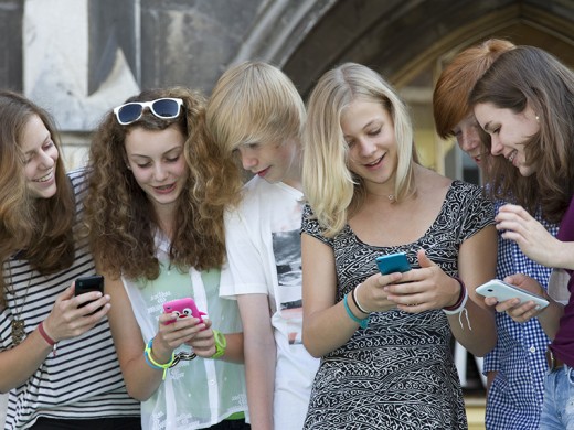 Teenage friends text messaging on cell phones
