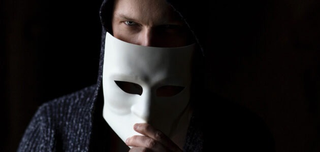 Mann mit Maske vor dem Gesicht als Symbol für Anonymität