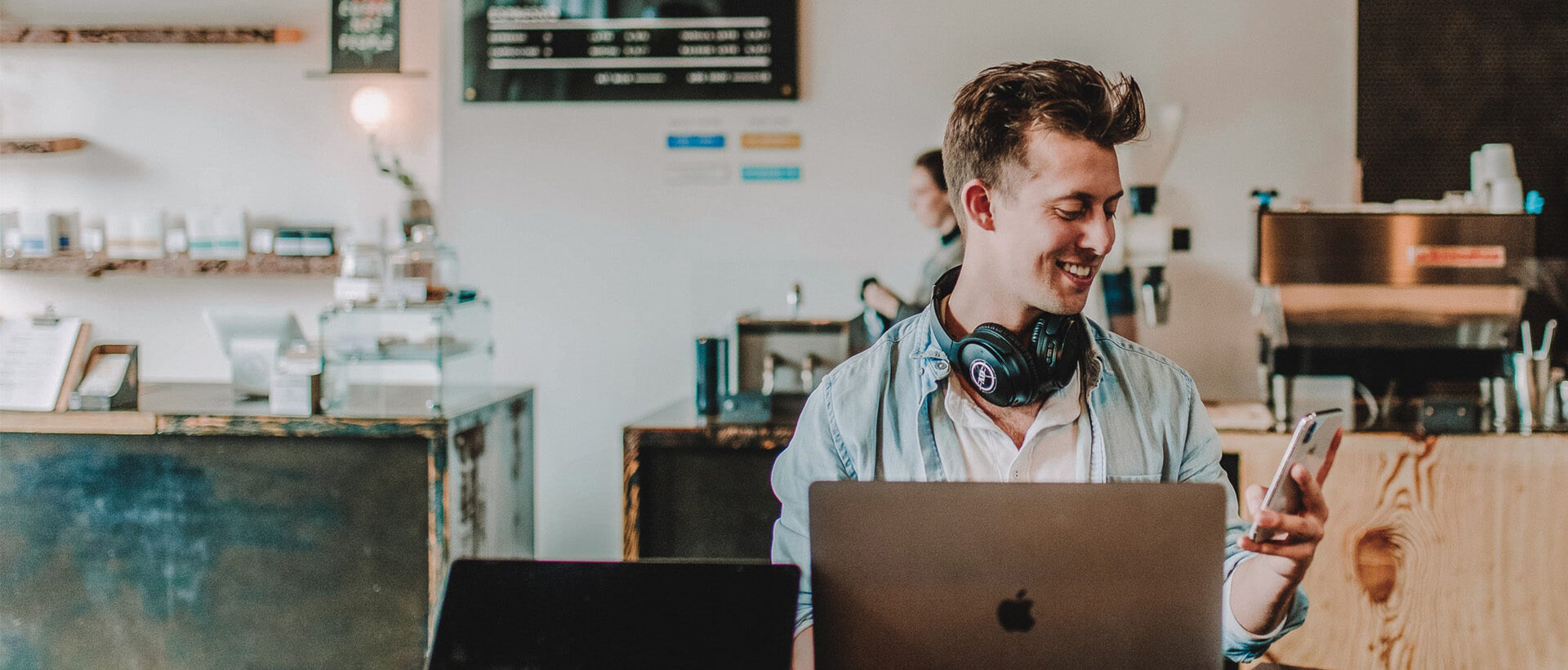 Lachender junger Mensch vor Computer in hippem Cafe