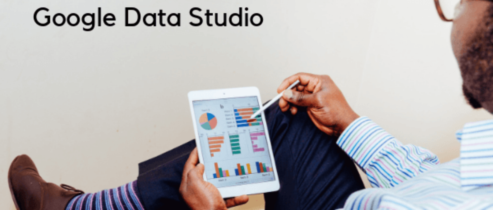 Google Data Studio ist der Titel des Bildes. Ein Mann sitzt und schaut sich ansprechend gestaltete Datenberichte an.
