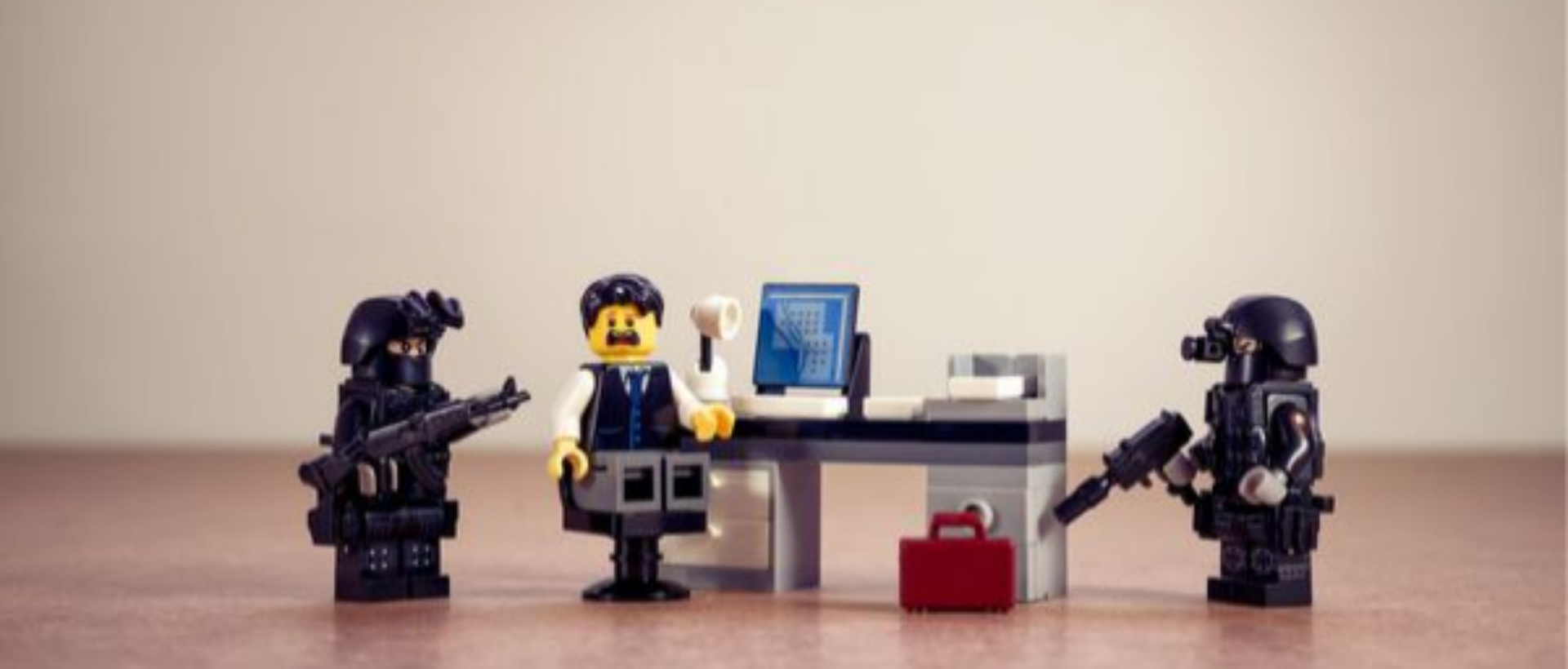 Lego Männchen die eine Situation darstellen, bei der zwei FBI Agenten einen Angestellten der in an einem Büro Tisch vor einem Computer sitzt mit Waffen bedrohen, um Anti Personas darzustellen für einen Blogpost von Xeit