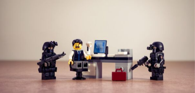 Lego Männchen die eine Situation darstellen, bei der zwei FBI Agenten einen Angestellten der in an einem Büro Tisch vor einem Computer sitzt mit Waffen bedrohen, um Anti Personas darzustellen für einen Blogpost von Xeit