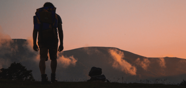 Mann beim wandern mit grossartiger Aussicht auf den Sonnenuntergang und Berge zur versinnbildlichung einer User Experience