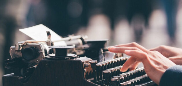 Alte Schreibmaschine, die von einer Person bedient wird, sinnbildlich für das Texten für Websites und Apps