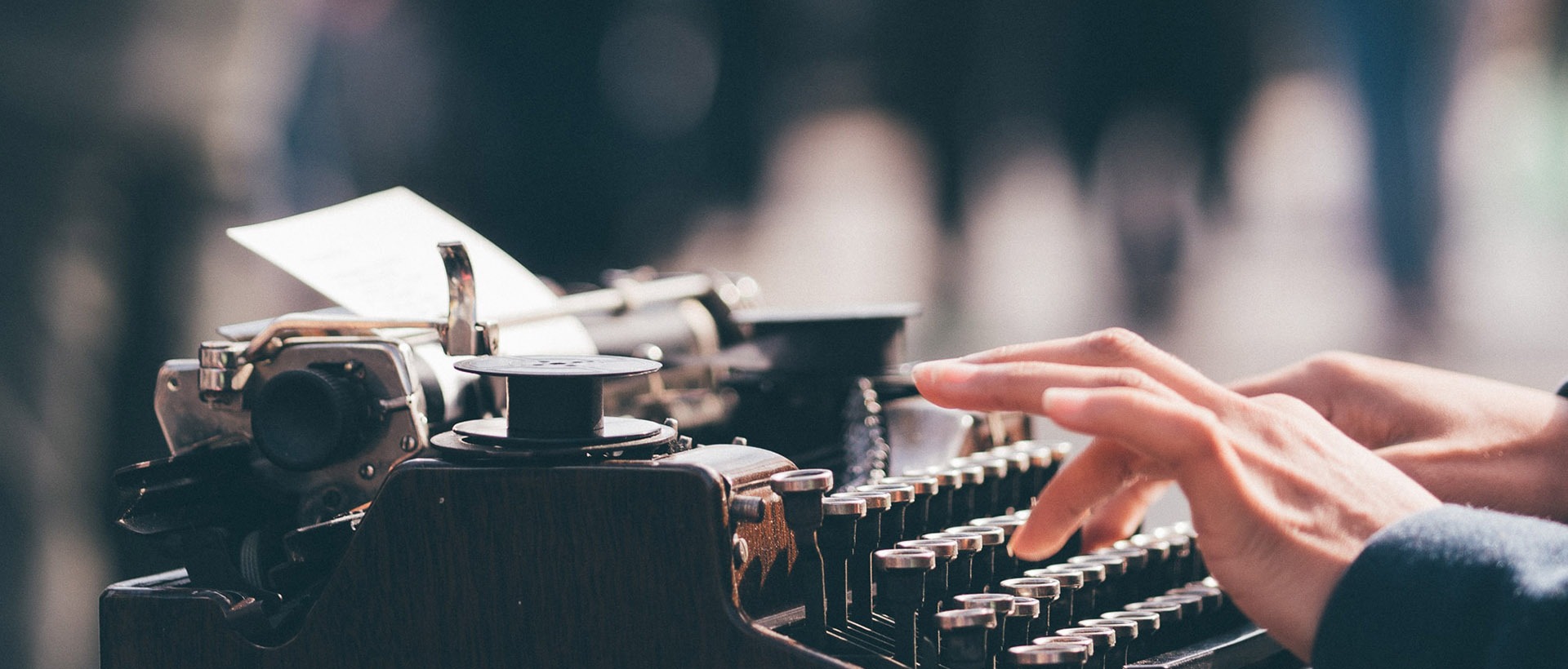 Alte Schreibmaschine, die von einer Person bedient wird, sinnbildlich für das Texten für Websites und Apps