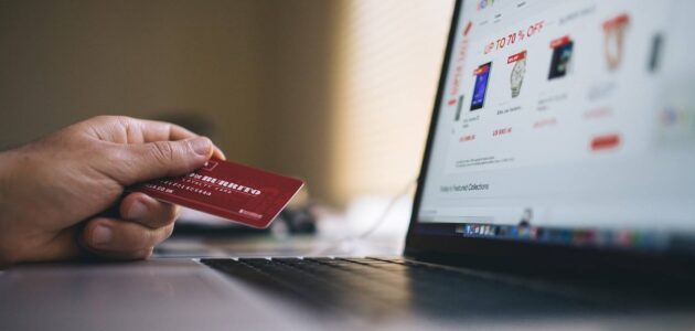 Ein Foto von einem Offenen Laptop und einer Hand, die eine Kreditkarte bereithält, steht sinnbildlich für Social Commerce