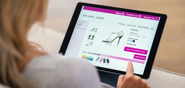 Eine Frau sieht sich im Online-Shop Schuhe an und liest den Produkttext