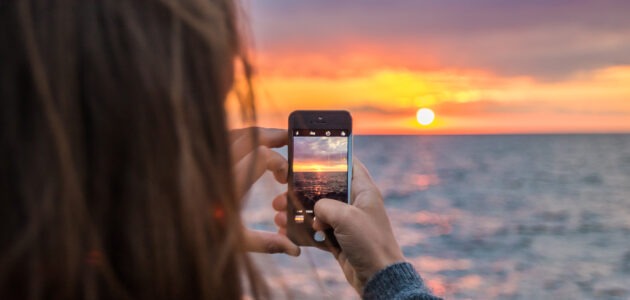 Junge Frau nimmt Foto des Sonnenuntergangs auf für Social Media.