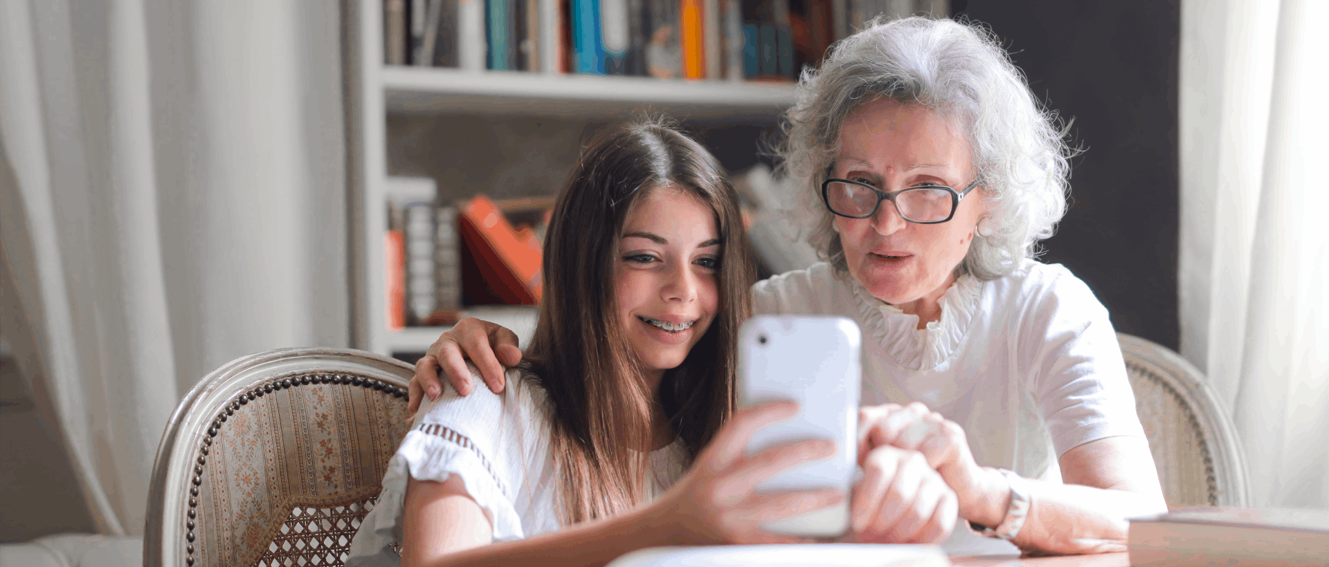 Enkelin und Grossmutter schauen auf Handy sinnbildlich für Senioren, die im Internet unterwegs sind und die Anforderungen an die Usability einer Website für Senioren xeit