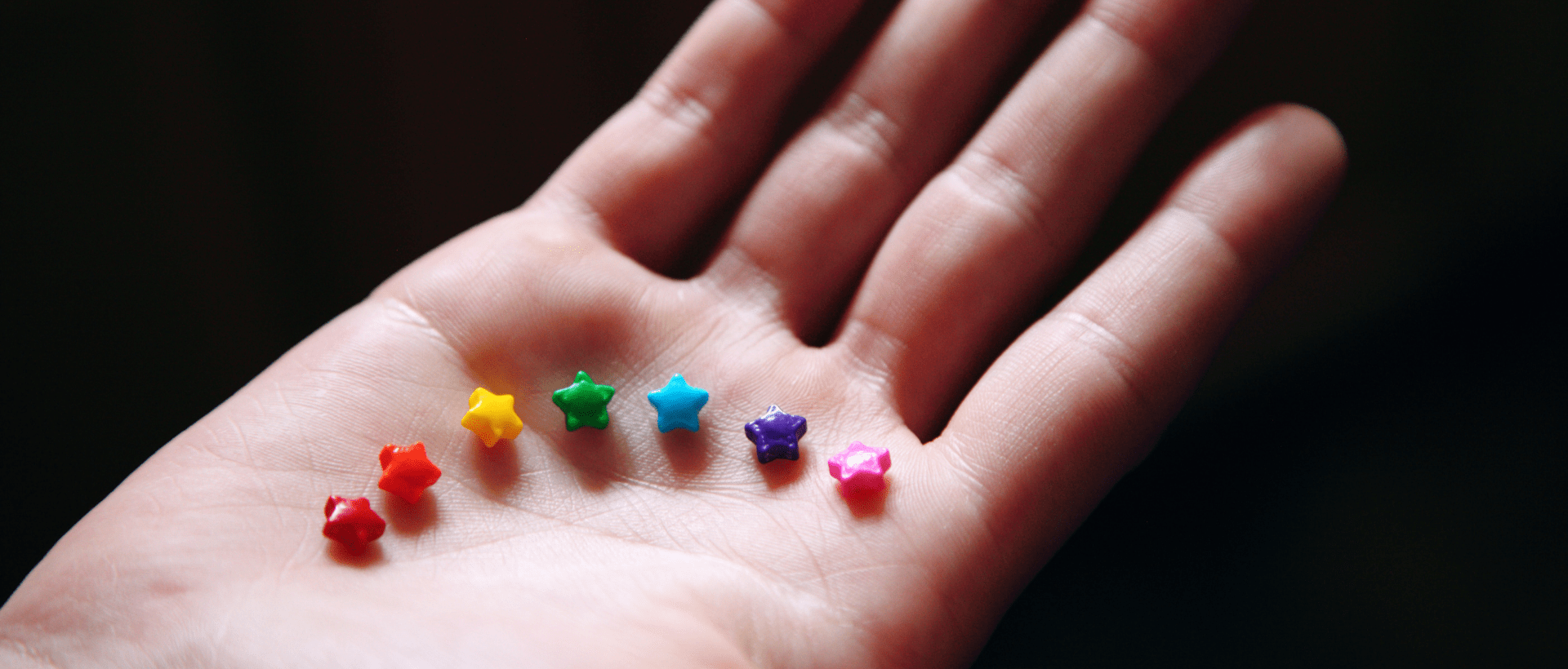 7 farbige Sternchen liegen auf einer Hand. Sie symbolisieren die Geschlechtsidentitäten. der Duden hat neue Regeln hinsichtlich Gendern erlassen, die sich auch aufs Marketing auswirken.
