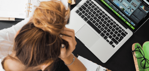 Eine Frau sitzt mit dem Kopf im Händen vor einem Laptop