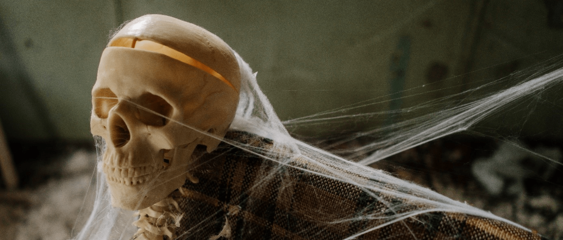 Ein Skelett sitzt auf einem alten Sofa mit Spinnenweben sinnbildlich für Horror und Storytelling