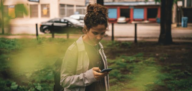 Ein junges Mädchen, der Generation Z, das auf ihr Handy schaut und die Nutzung von Plattformen darstellen soll.