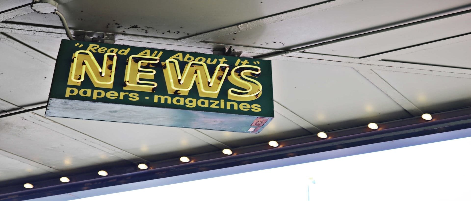 Von der Decke hängendes Schild mit gelber Aufschrift "read all about it" NEWS