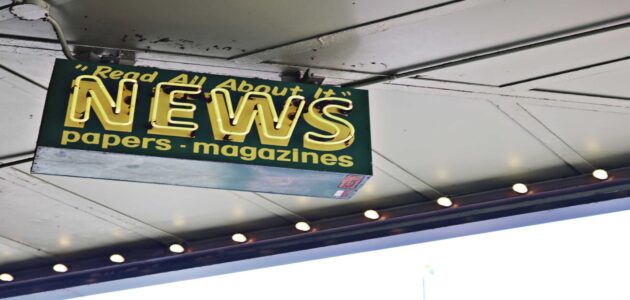 Von der Decke hängendes Schild mit gelber Aufschrift "read all about it" NEWS