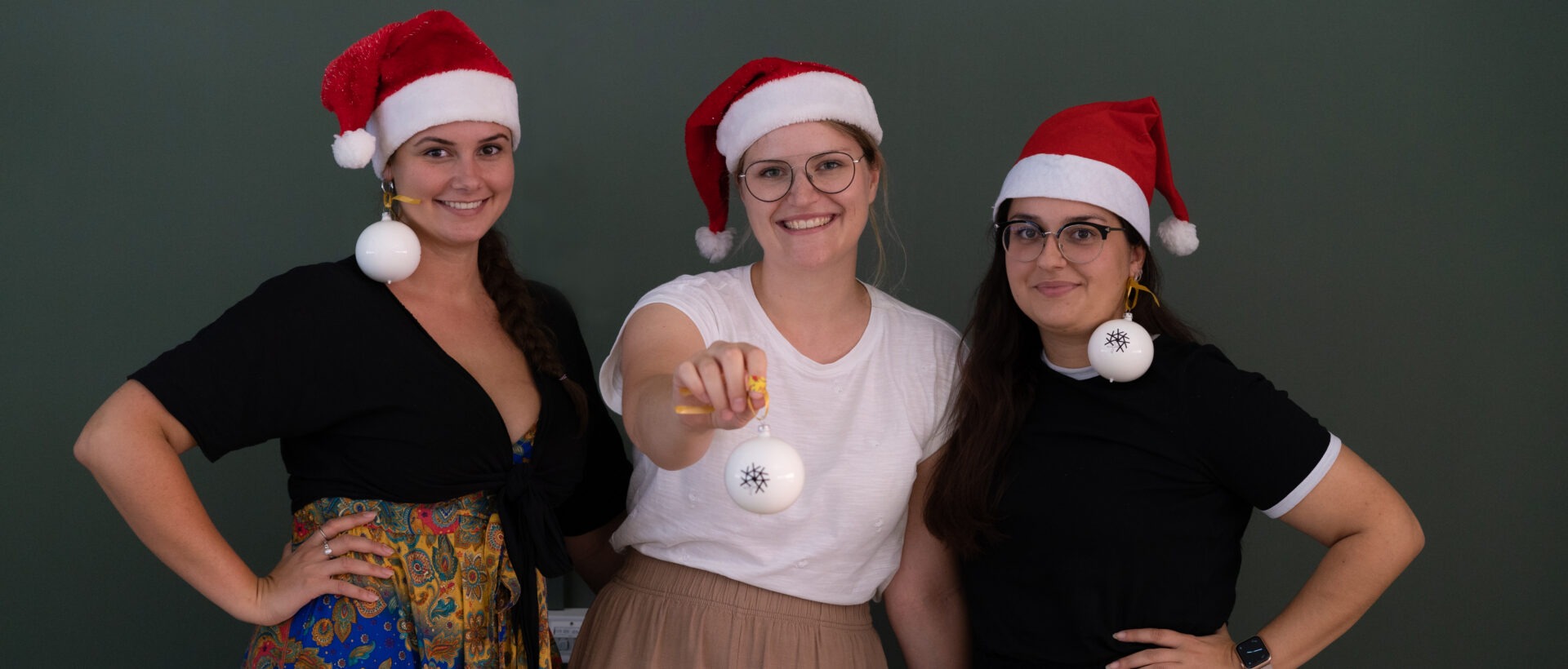 Content Producerinnen Jill, Sina und Nuria mit Santaclausmützen auf dem Kopf und Weihnachtskugeln, xeit