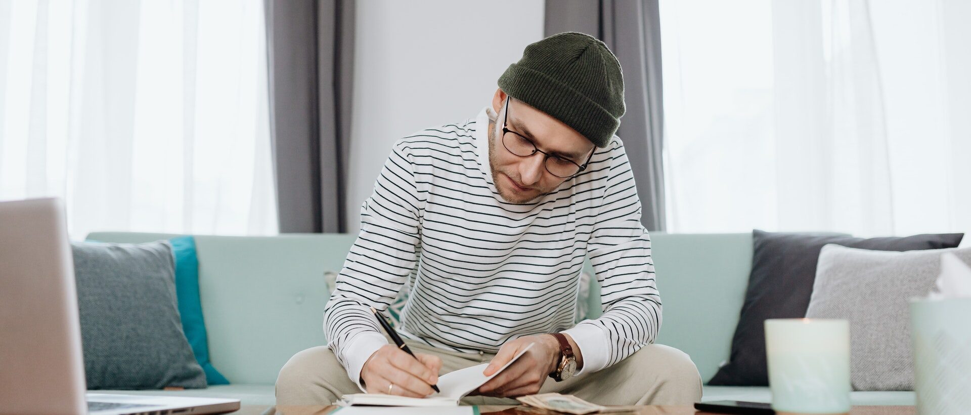 Mann sitzt auf einem Sofa und schreibt Gedanken rund um einen Business Case in sein Notizbuch