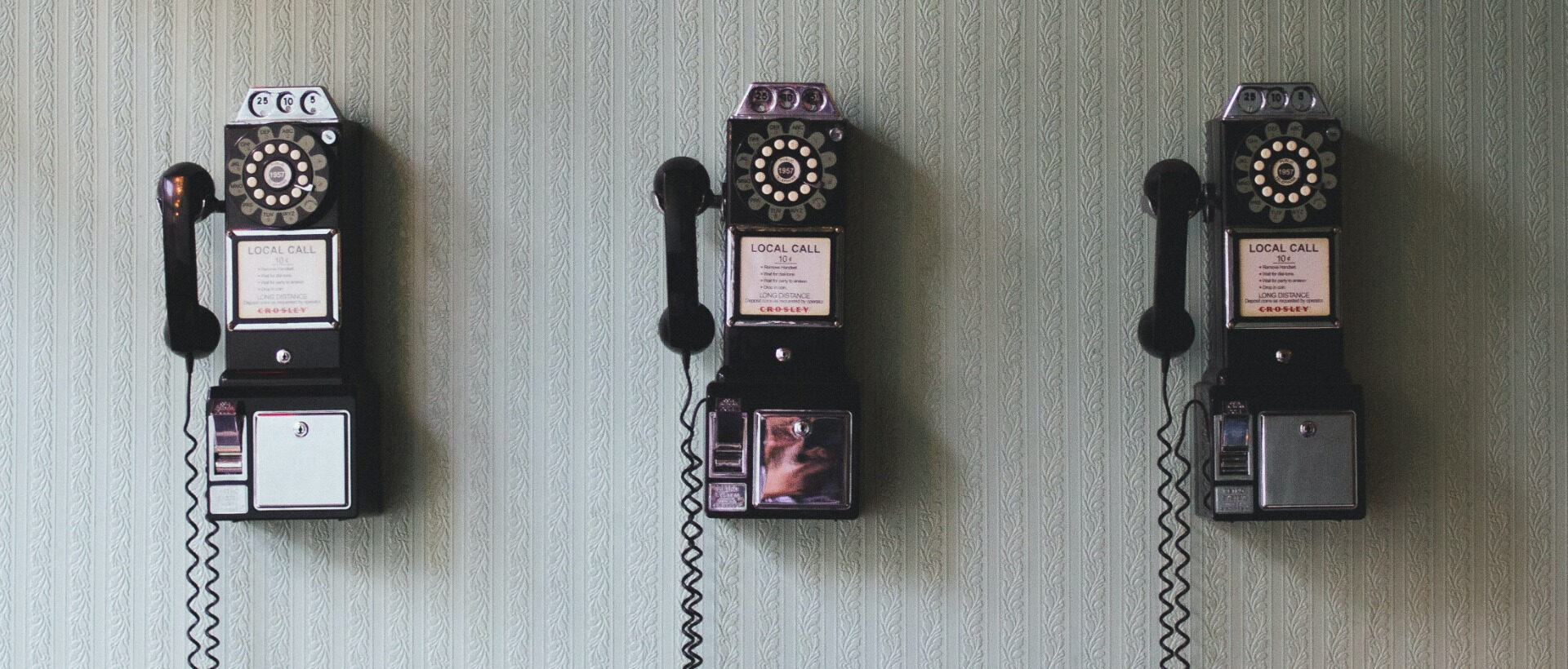 Drei alte Telefonapparate an einer Wand stehen ironisch-symbolisch für die Kommunikation mit der Generation Z, xeit