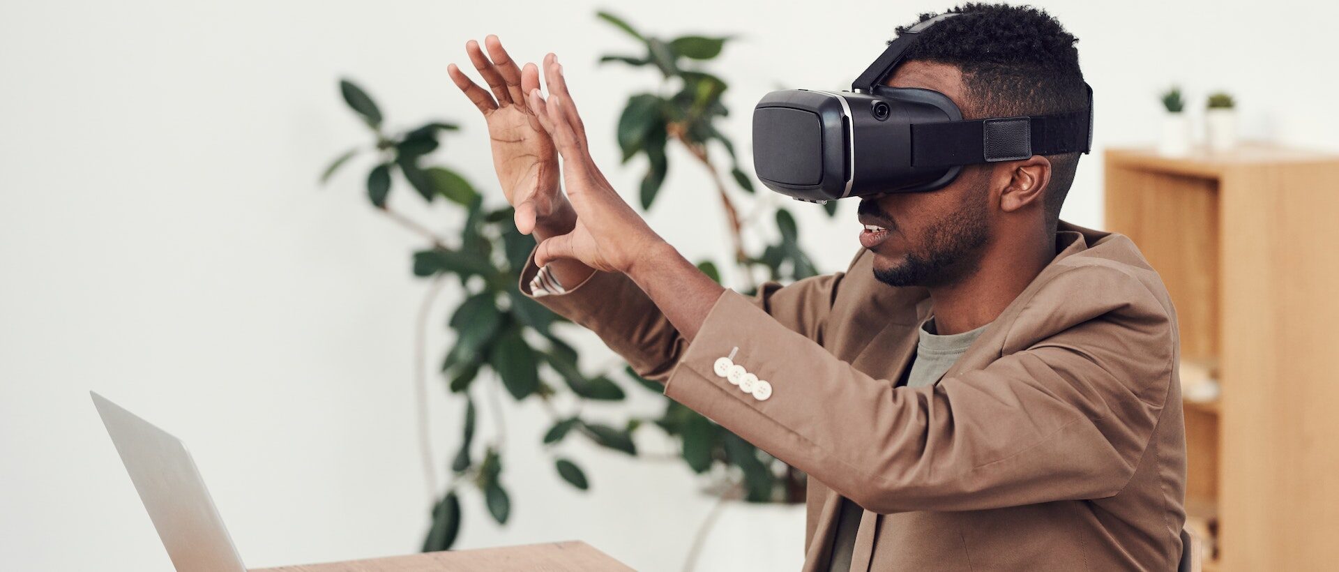 Bild von Mann der VR Brille trägt und etwas virtuell greifen will