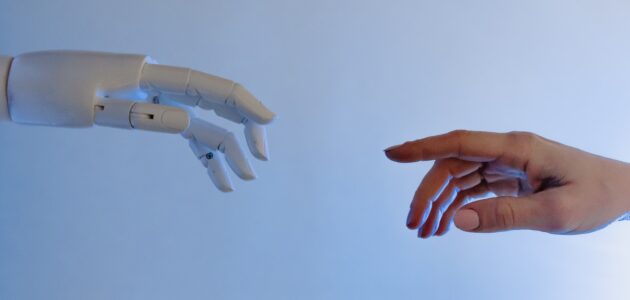 Roboterhand versucht menschliche Hand zu berühren als Sinnbild für künstliche Intelligenz