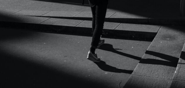 Schwarz-weiss-Bild, eine Person mit Sneakern auf einer Strasse, rechts eine Treppe nach oben, steht symbolisch für Marketing-Vorsätze